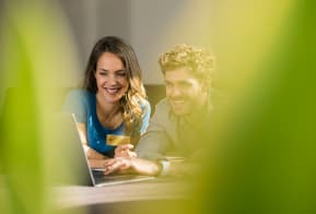 smiling-couple-shopping-online-with-laptop-on-sofa-2024-09-15-21-55-09-utc